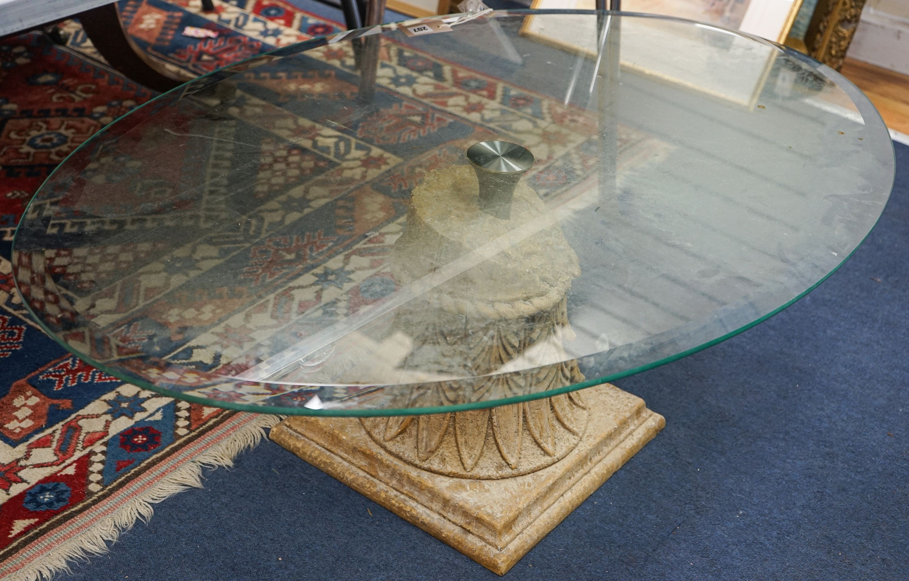 A contemporary oval glass top coffee table on simulated carved stone base, width 118cm, depth 79cm, height 41cm